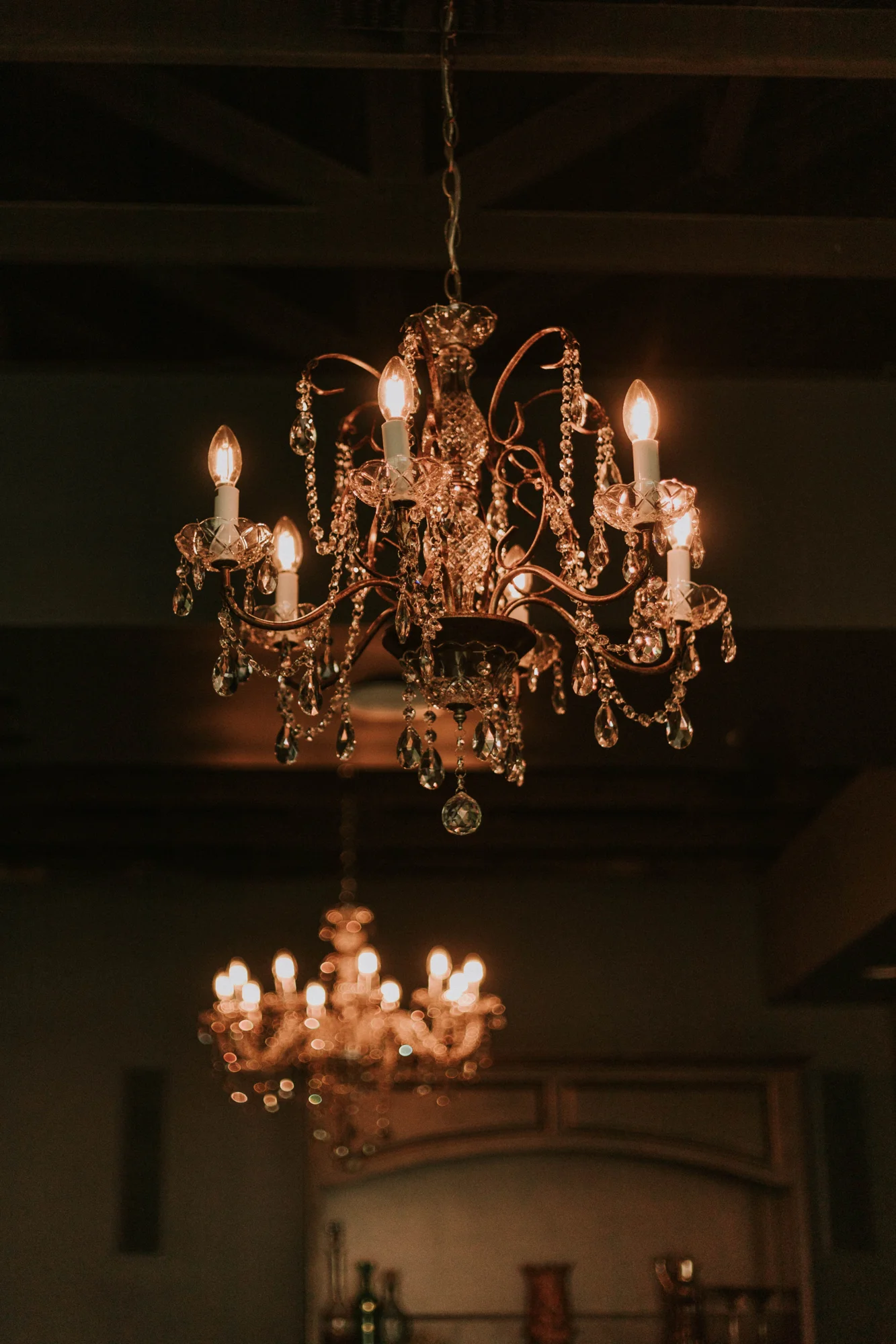A brass chandelier glowing against the dark ceiling